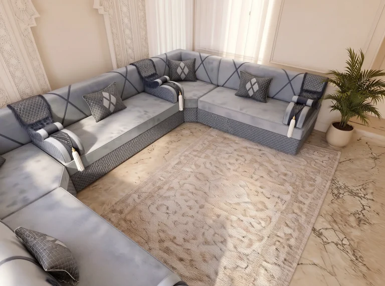 High-angle corner view of a grey velvet Arabic majlis with quilted cushions on three sides of a cream rug