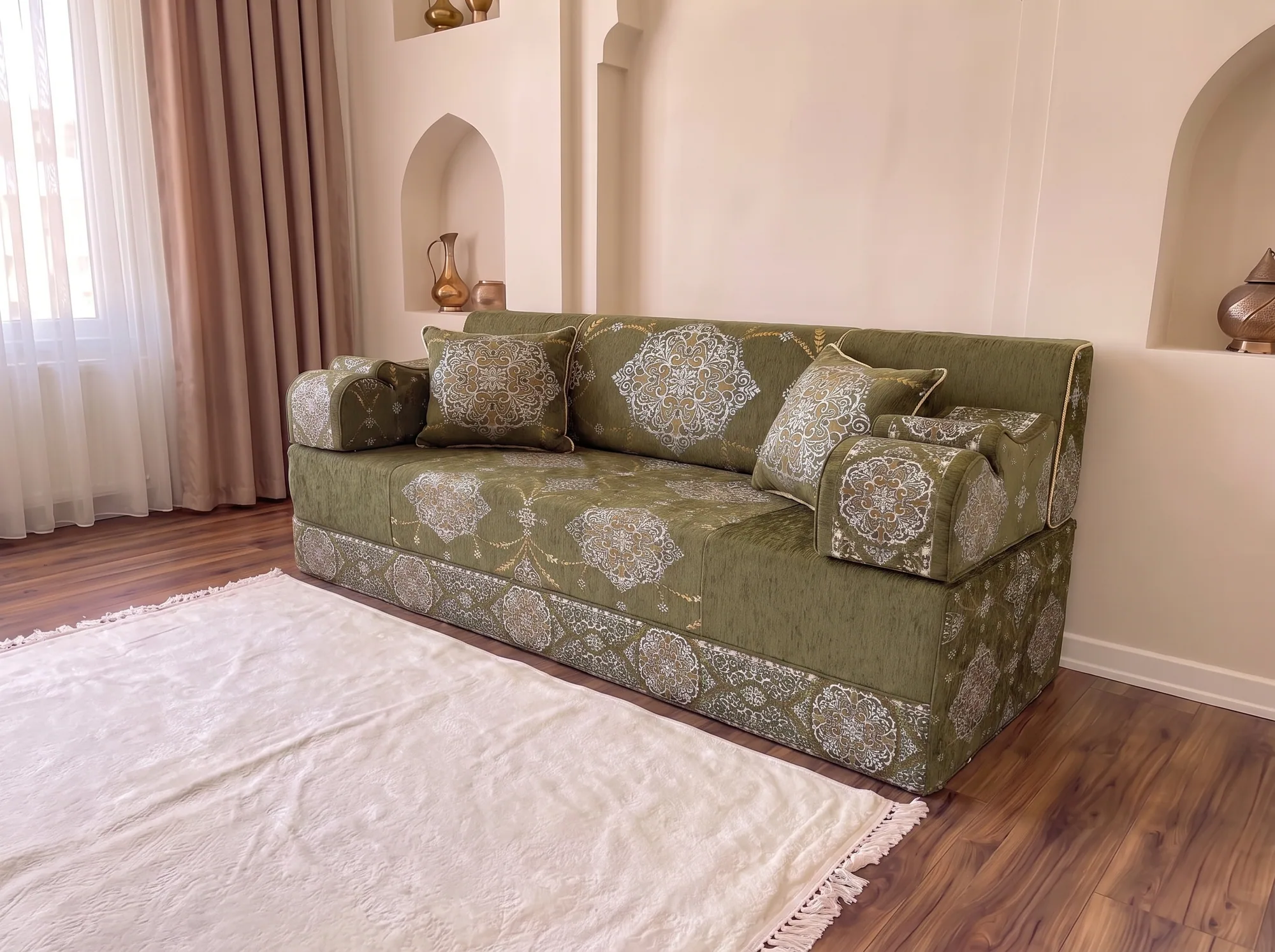 Khaki green medallion Arabic majlis viewed from a low left angle with two throw pillows and a white fringed rug