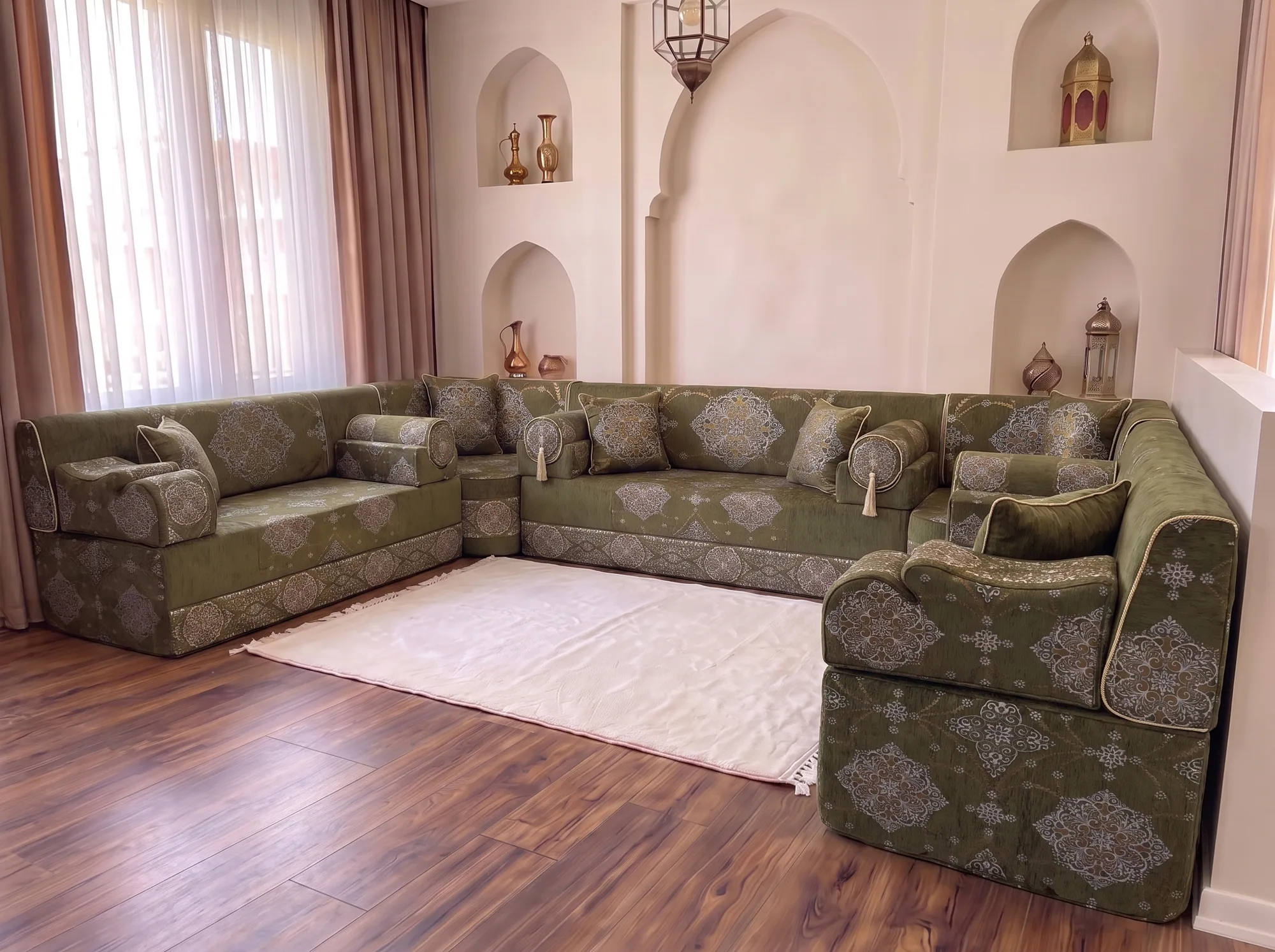 Khaki green medallion majlis sofa set in a U shape seen from a low side angle around a white fringed rug