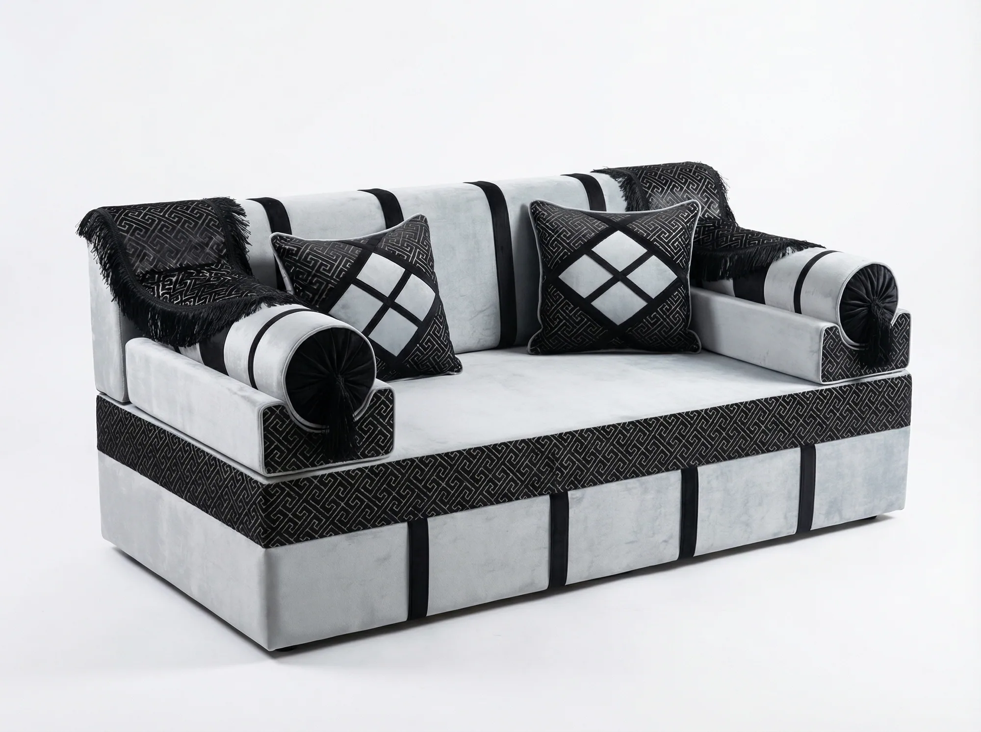 Light grey velvet majlis seating piece with black key-pattern jacquard bands, black fringed throws and two cushions