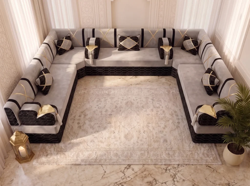 Overhead view of a U-shaped light grey and black jalsa with gold accents framing a cream rug