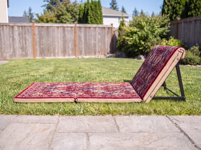 Side profile of a maroon folding Arabic sunbed lounger with its backrest raised on a black frame