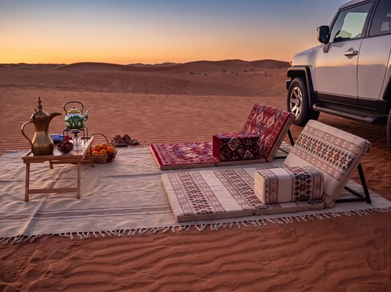 Maroon and beige folding Arabic sunbed loungers on one cream fringed rug at sunset next to a 4x4