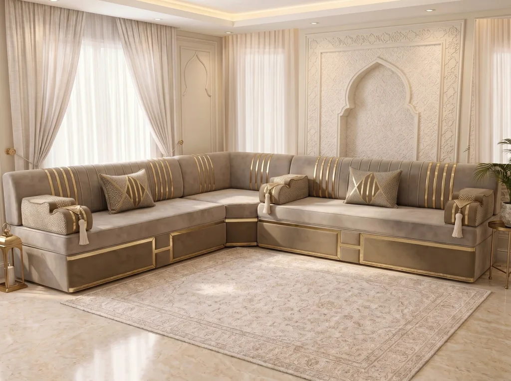 Beige velvet majlis sofa in an L shape with gold-striped backs and gold-framed bases on a beige rug by a carved arch