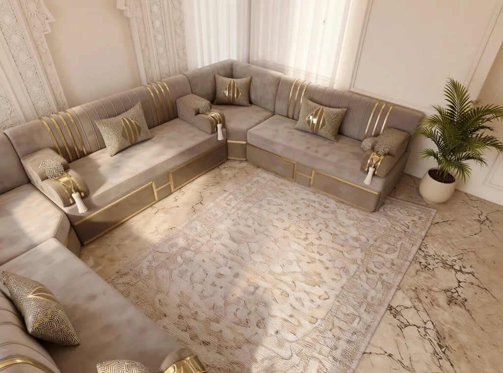 Overhead corner view of a beige velvet Arabic majlis with gold-striped backs wrapping a beige rug on a marble floor