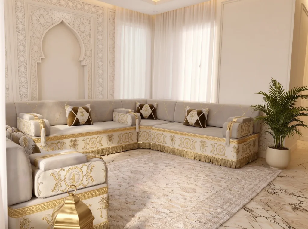 Beige Arabic jalsa in a U shape with gold-embroidered cream bases, seen over a foreground armrest and a brass lantern