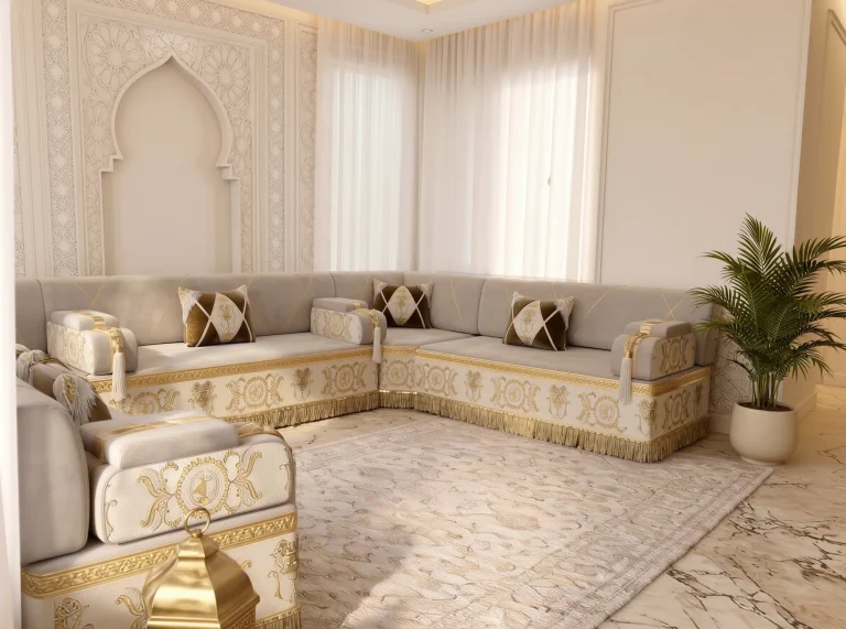 Beige Arabic jalsa in a U shape with gold-embroidered cream bases, seen over a foreground armrest and a brass lantern