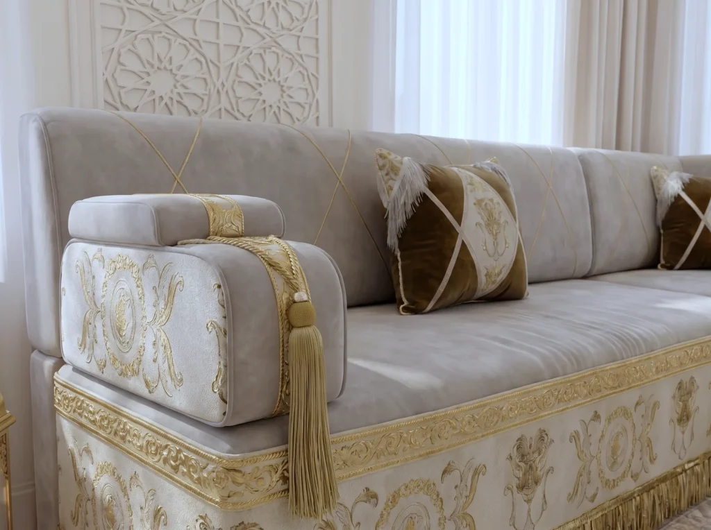 Close-up of a beige velvet majlis sofa armrest with gold baroque embroidery, a gold tassel and brown fringed pillows