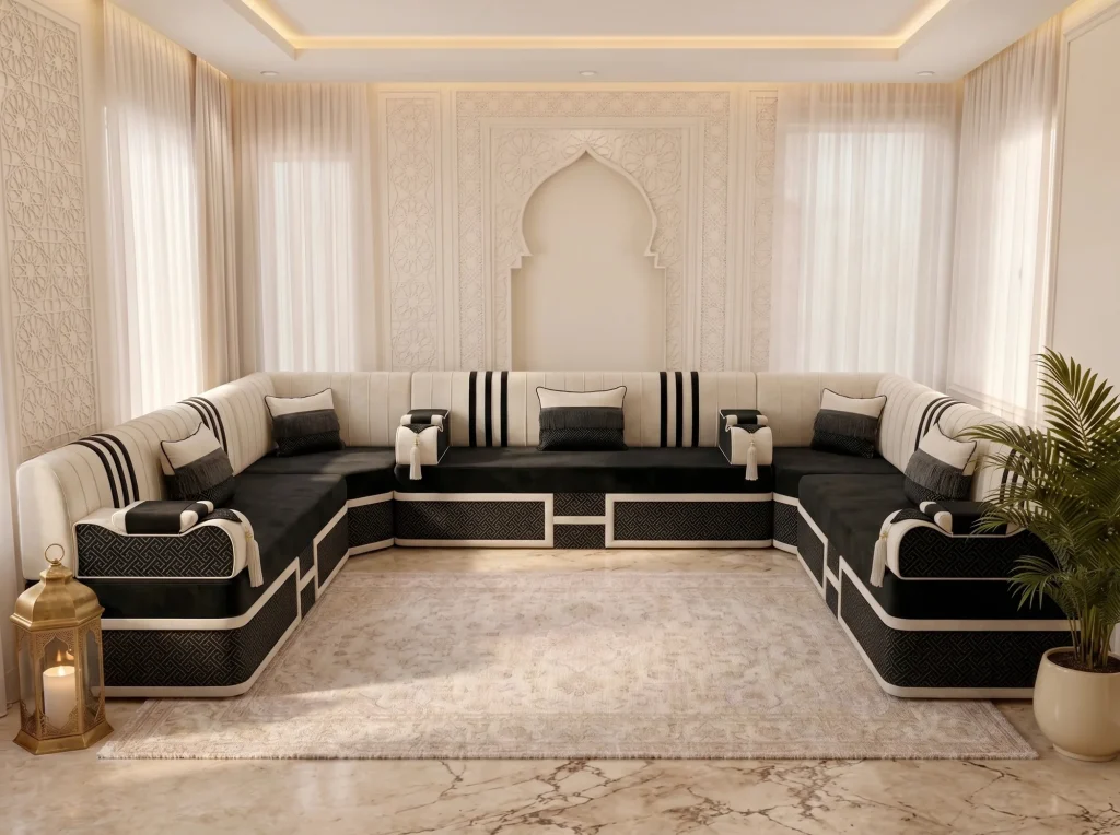 Black velvet majlis sofa in a U shape with cream black-striped backs and fringed pillows, seen from the front