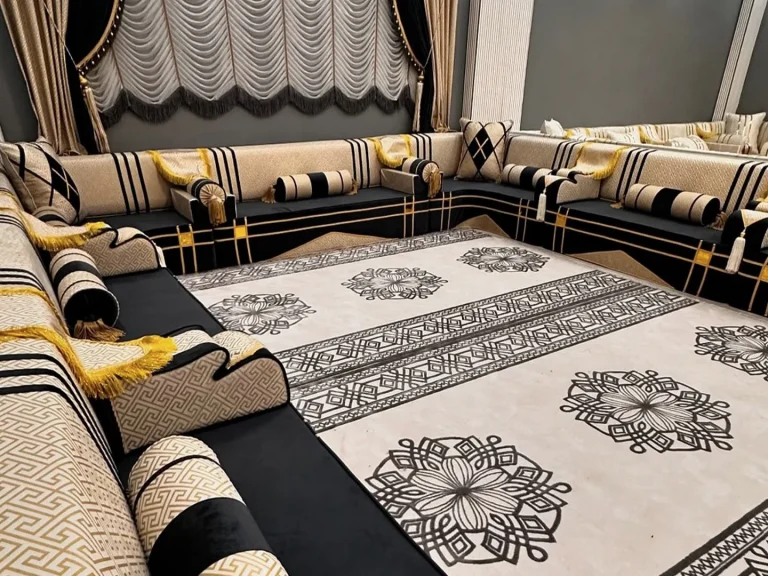 Black velvet Arabic jalsa with cream key-pattern backs, striped bolsters and yellow fringe around a rosette-pattern rug