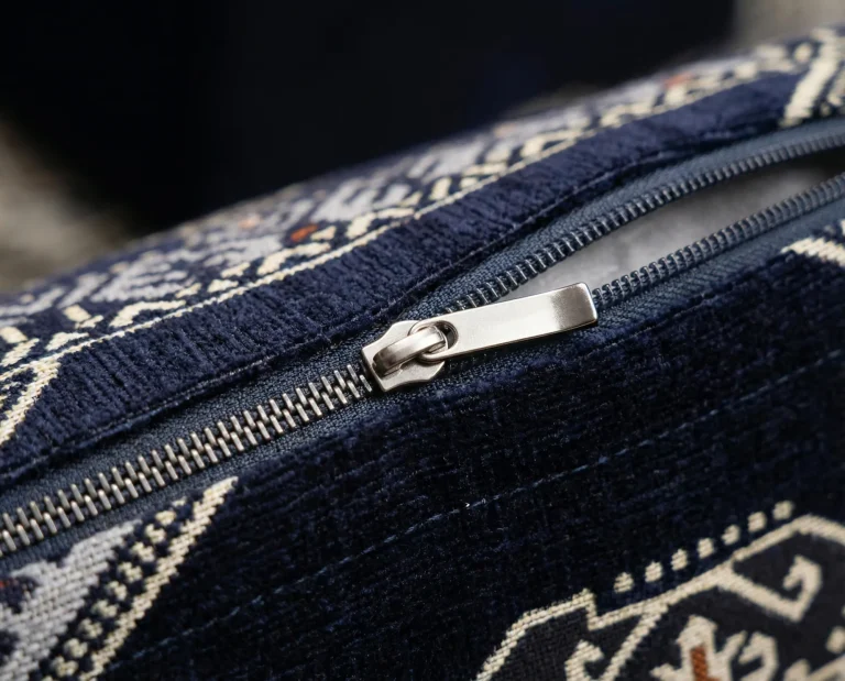 Partly open metal zip on a navy chenille upholstery cushion cover, showing the white inner lining beneath