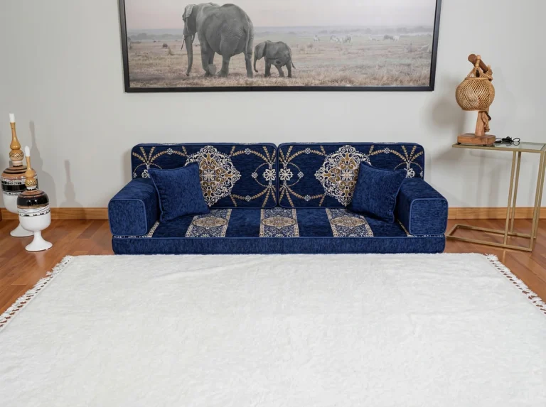 Navy chenille Arabic floor sofa with gold medallion back cushions, shown alone on an empty white rug