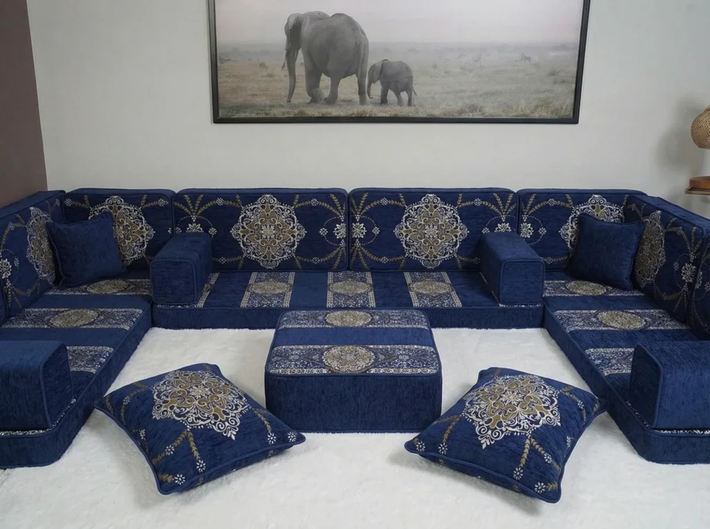 Navy chenille diwan floor sofa in a U shape with gold medallion back cushions around a matching ottoman