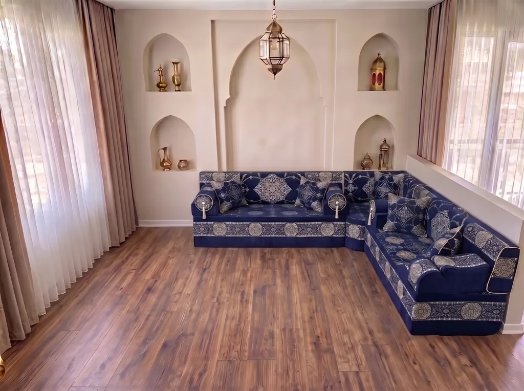Navy L-shaped majlis sofa with silver medallion upholstery and tasselled bolsters on a wooden floor