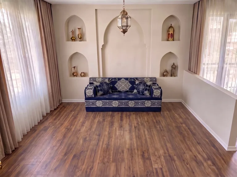 Navy majlis sofa with silver medallion pattern standing alone on a wooden floor below arched niches
