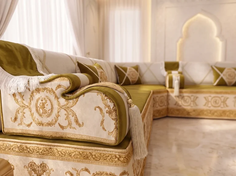 Close-up of an ivory armrest with gold baroque scrollwork, olive piping and a tassel on a majlis sofa