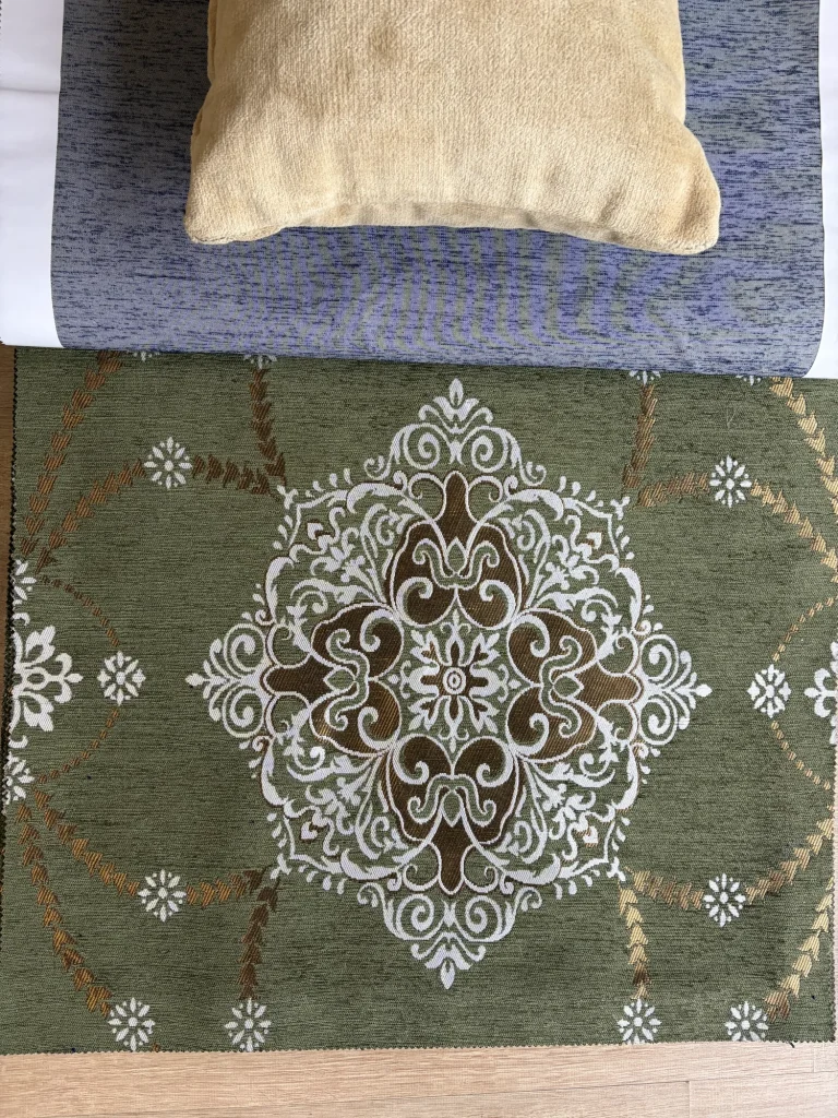 Olive green chenille upholstery fabric swatch with one large white and bronze woven medallion