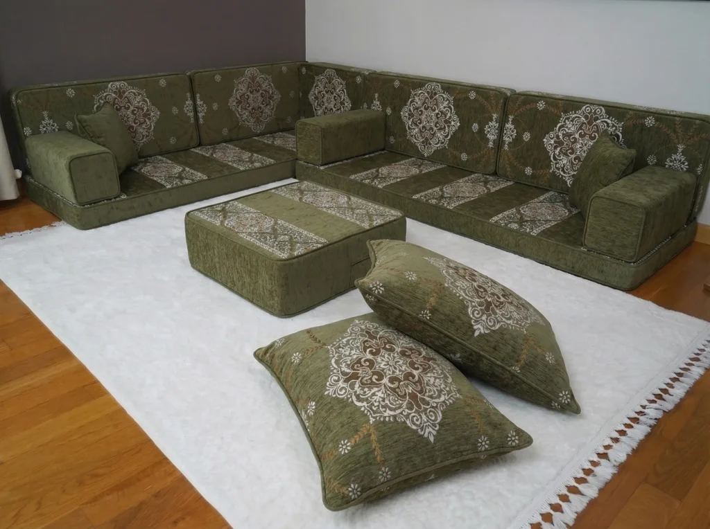 Olive green diwan floor sofa in an L shape with cream medallion cushions, ottoman and two floor cushions