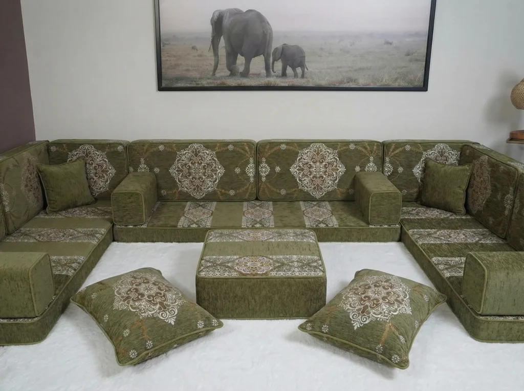 An olive green U-shaped floor sofa with cream medallion cushions and a matching ottoman