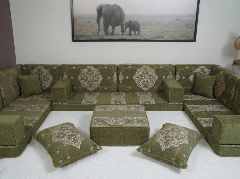 Olive green Arabic floor couch in a U shape with cream medallion cushions and an ottoman