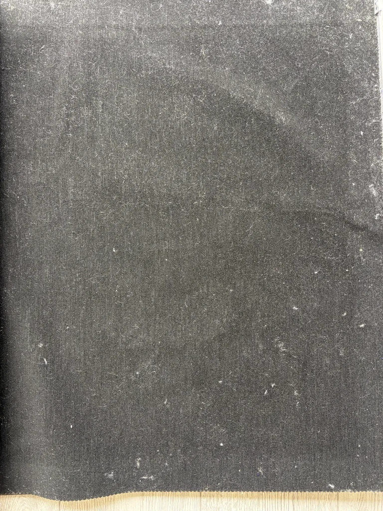 Plain charcoal woven upholstery fabric sample for seat covers, photographed flat with visible lint