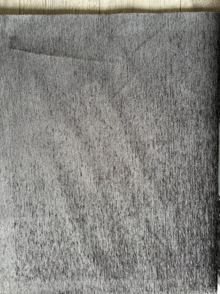 Plain mid-grey chenille upholstery fabric swatch, showing its slubbed woven texture up close