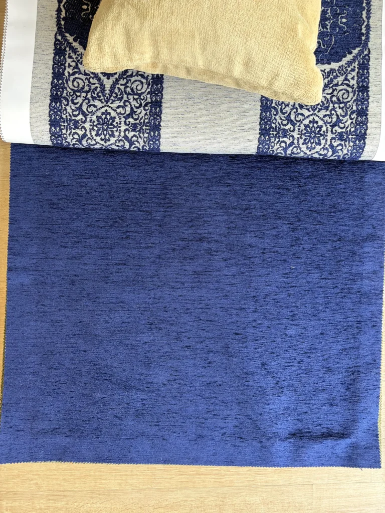 Plain navy chenille upholstery fabric swatch for seat cushions, laid flat on a light wood floor