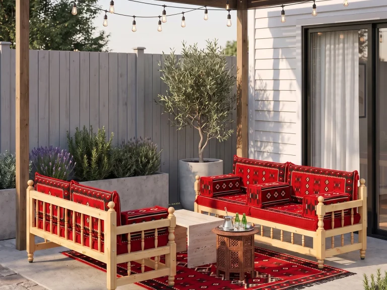 Two wooden benches with red kilim cushions on a backyard patio with an olive tree, lavender and a tea tray