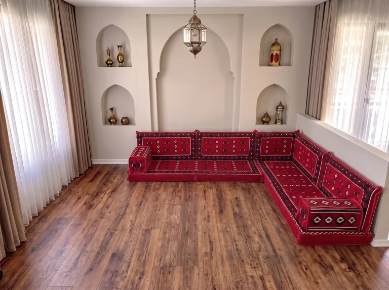 Red Arabic floor sofa with black and white sadu motifs in an L-shaped corner layout on a bare wooden floor