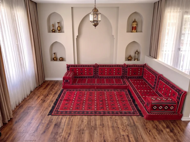Red sadu-pattern Arabic floor couch in an L shape with a matching red fringed rug in a room with arched niches