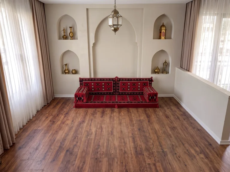 Red Arabic sofa with black and white sadu motifs standing alone on a wooden floor under an arched niche wall