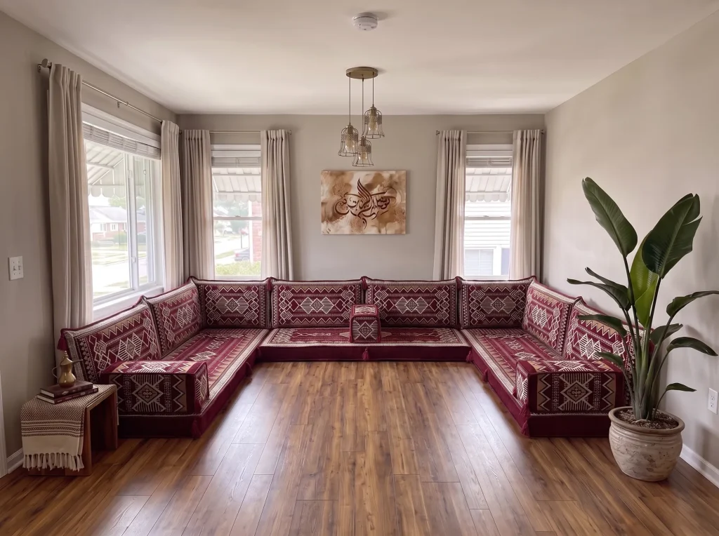 Burgundy and cream kilim U-shaped floor sofa set on a bare wood floor in a grey living room with Arabic calligraphy wall art