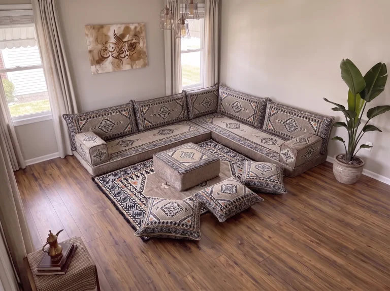 Taupe kilim Arabic floor sofa in an L shape viewed from above, with ottoman, patterned rug and three floor cushions