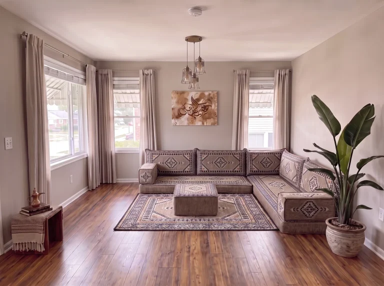 Taupe and black kilim L-shaped Arabic floor couch with matching rug and ottoman in a sunlit living room