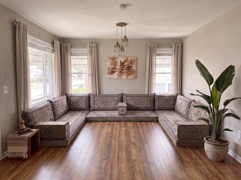 Taupe and black kilim U-shaped floor seating set on a bare wood floor in a sunlit living room with a tall potted plant