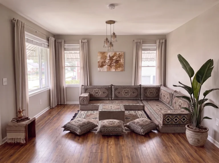 Taupe medallion L-shaped Arabic floor sofa with rug, ottoman and floor cushions in a neutral living room