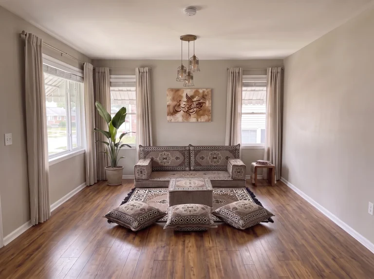 Taupe medallion single-row floor seating set with rug, ottoman and floor cushions in a neutral living room, wide room view