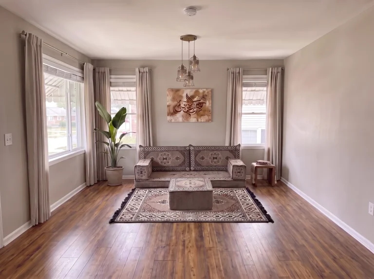Taupe medallion single-row Arabic sofa with matching rug and ottoman in a neutral living room, wide room view