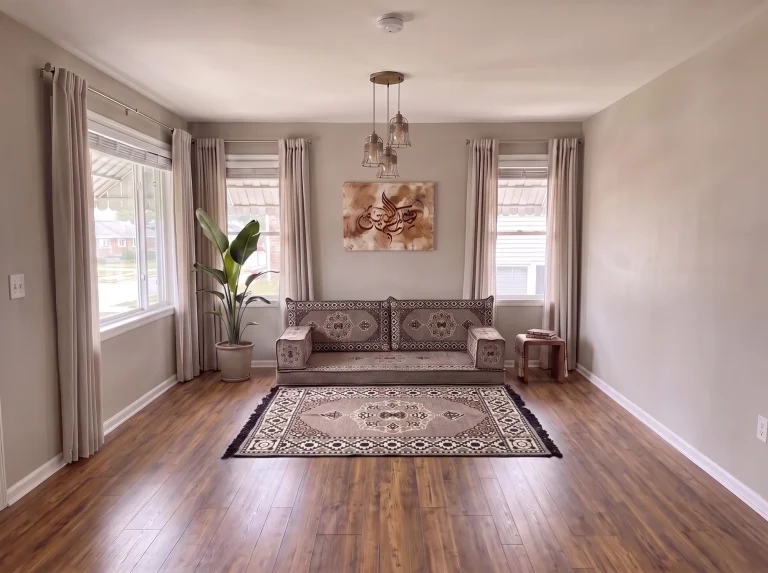 Taupe medallion single-row Arabic floor sofa with a matching fringed rug in a neutral living room, wide room view