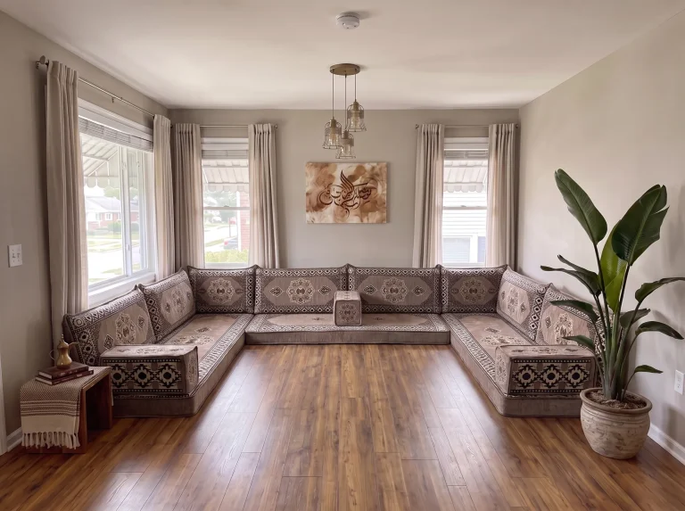 Taupe medallion U-shaped floor sofa set on a bare wood floor in a neutral living room with calligraphy art and pendant lamps