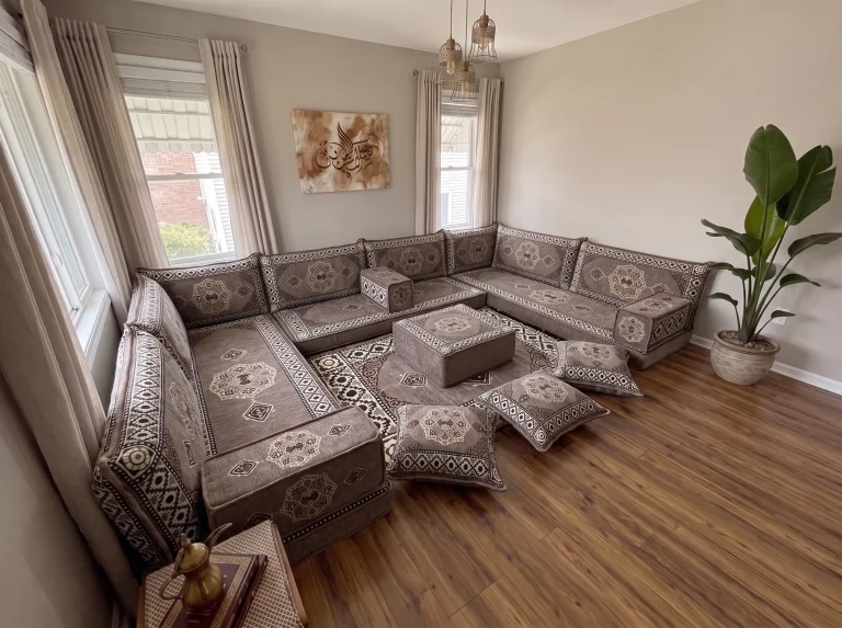 Taupe medallion U-shaped floor seating set with rug, ottoman and floor cushions in a neutral living room, high corner view