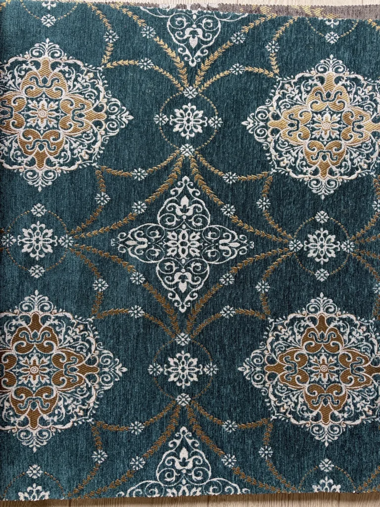 Teal chenille jacquard upholstery fabric with repeating white and gold medallions, shown full frame