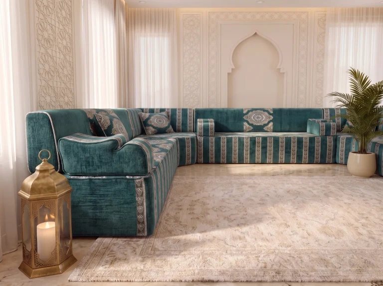 Low view past the teal velvet end of a U-shaped Arabic majlis toward a medallion backrest and arch wall