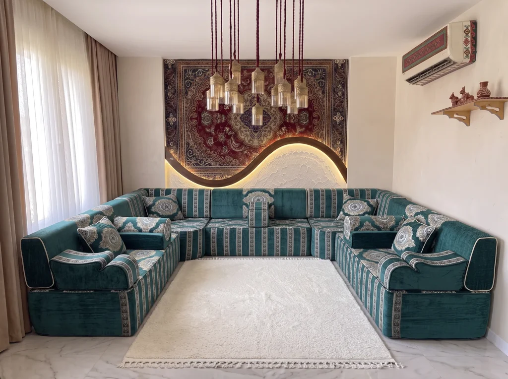 Teal velvet Arabic majlis with silver stripes and medallion cushions in a U shape around a white shaggy rug on marble