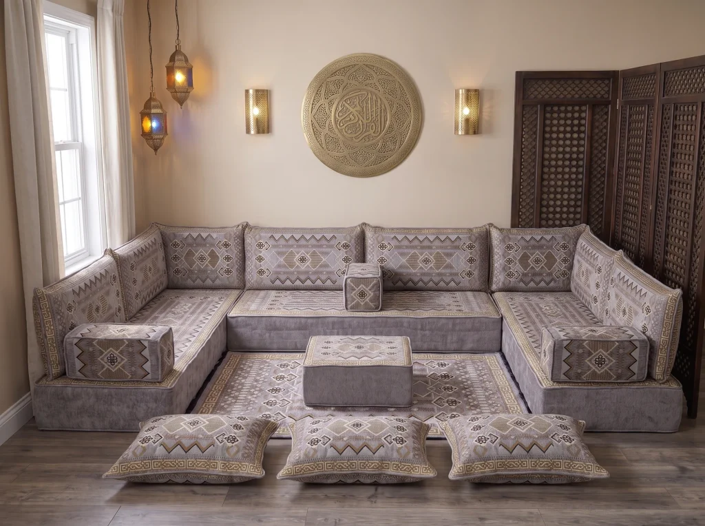 Thick gray and gold kilim Arabic floor sofa in a U shape with rug, ottoman and floor cushions below a brass wall plate