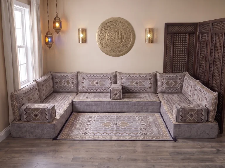 Thick gray and gold kilim Arabic floor sofa in a U shape with a matching kilim rug under a brass calligraphy wall plate
